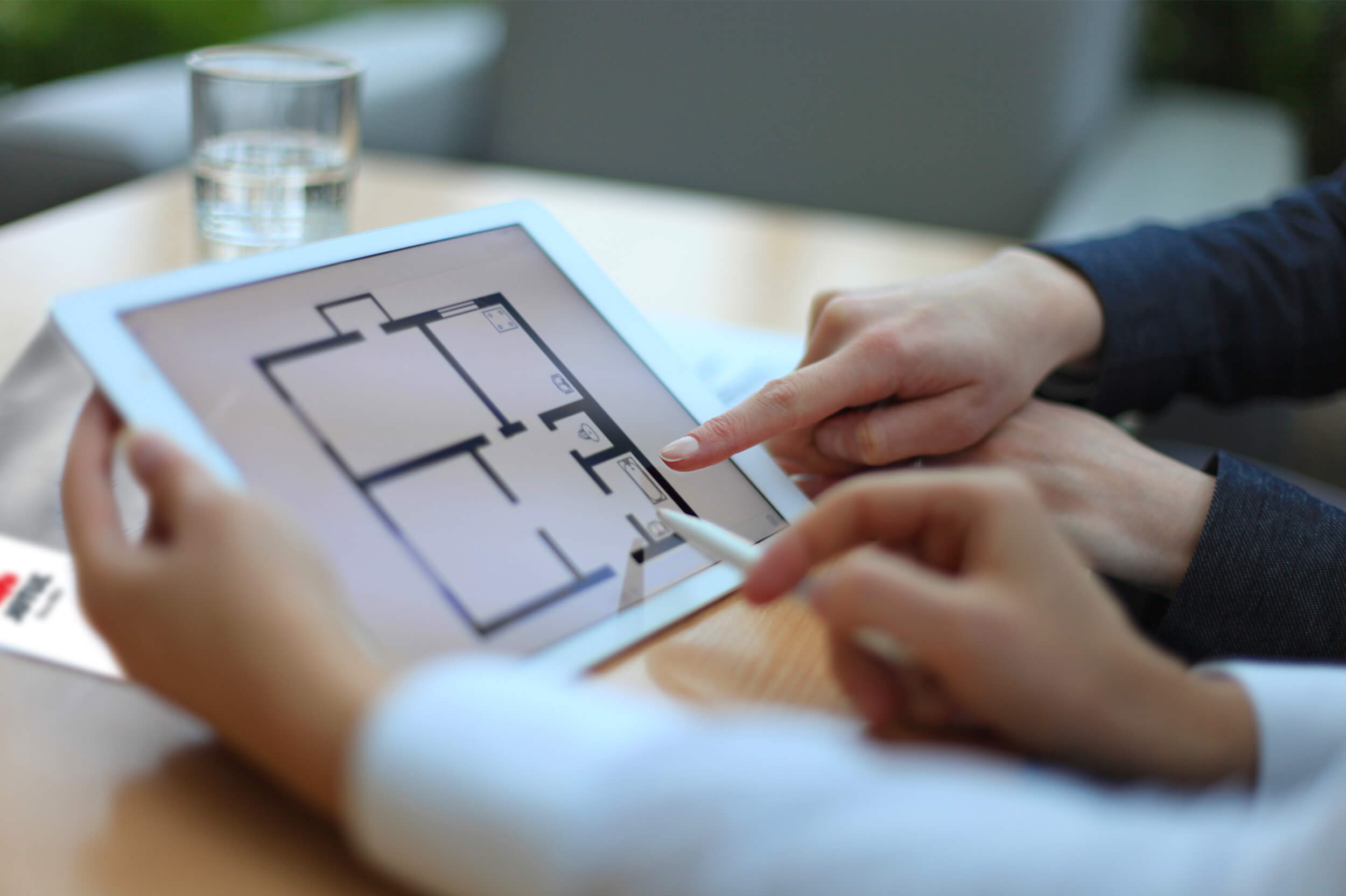 Hender som peker på iPad med ark med romfordeling i et hus.