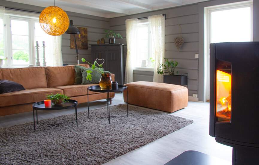 Vedovn i grå stue med tømmervegger og brun sofa