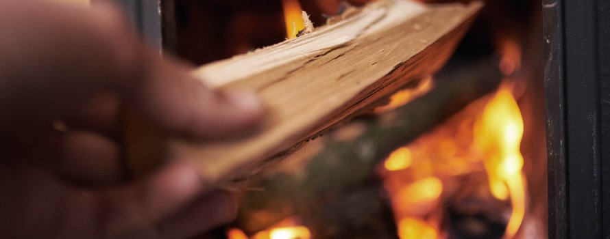 Hånd som legger ved i peisen