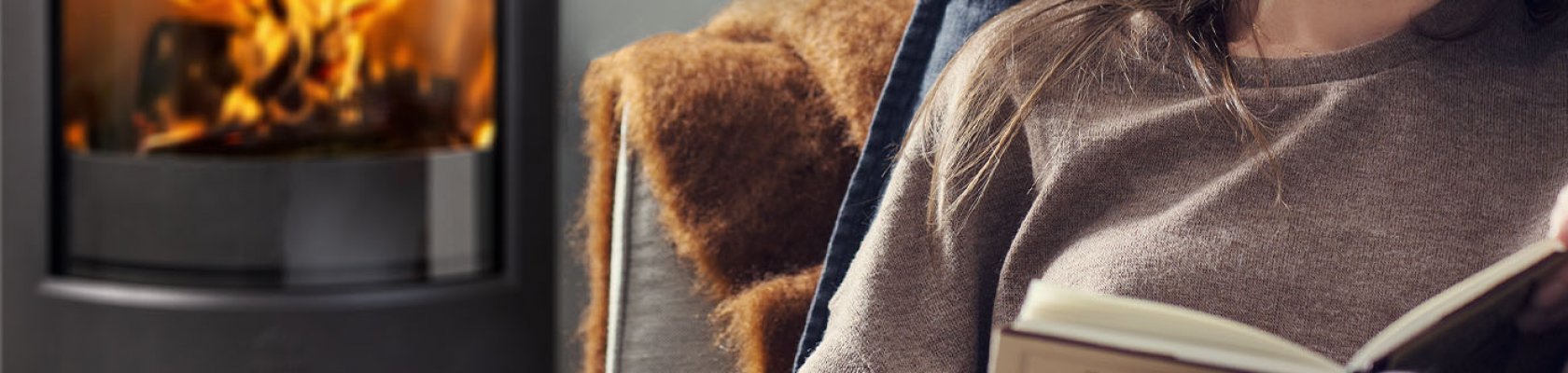 Dame som leser foran peisen