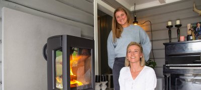 To unge jenter som står ved siden av vedovnen Jøtul F 167