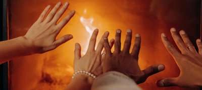 Hender som varmer seg på peisen