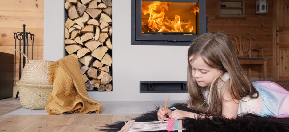 Jøtul I FR 520 peisinnsats i støpejern på hytte, med vednisje og jente foran