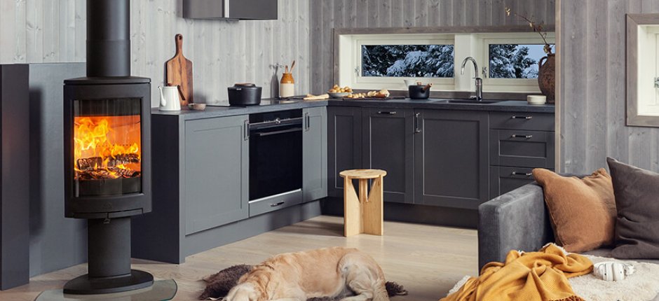 Jøtul F 373 Advance vedovn i sort støpejern plassert på kjøkken med hund foran.