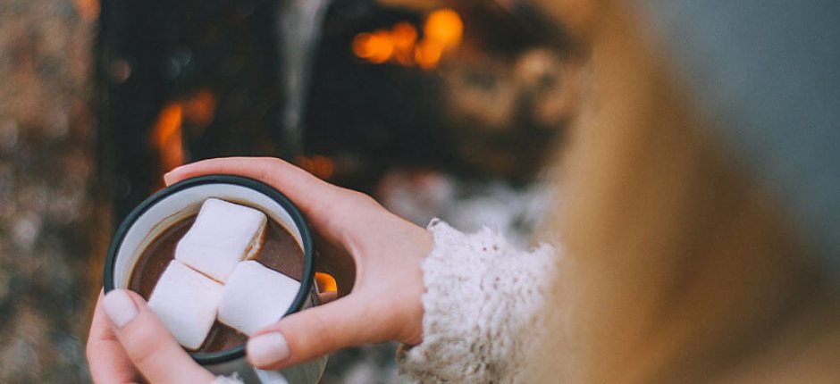 Jente drikker kakao ved bålet 