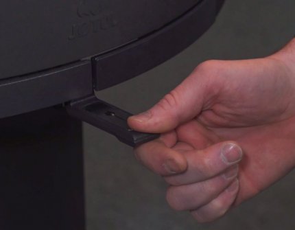 Hånd som justerer luftventil på Jøtul vedovn