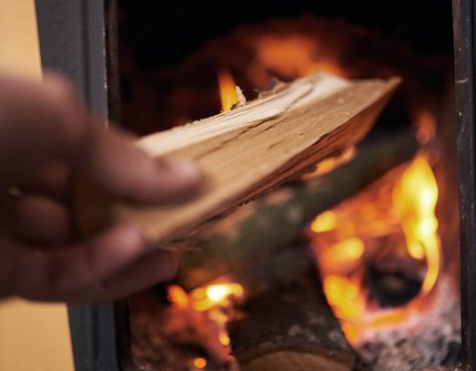 Hånd som legger ved i peisen