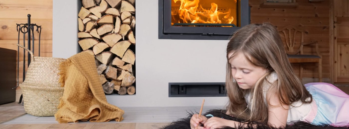 Jøtul I FR 520 peisinnsats i støpejern på hytte, med vednisje og jente foran