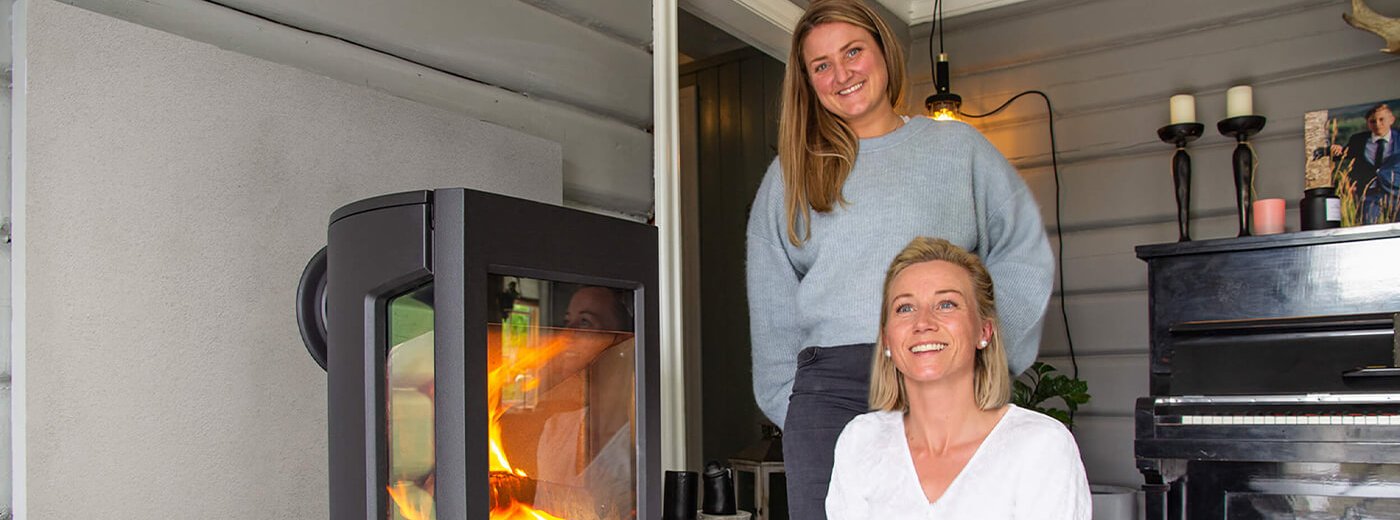 To unge jenter som står ved siden av vedovnen Jøtul F 167