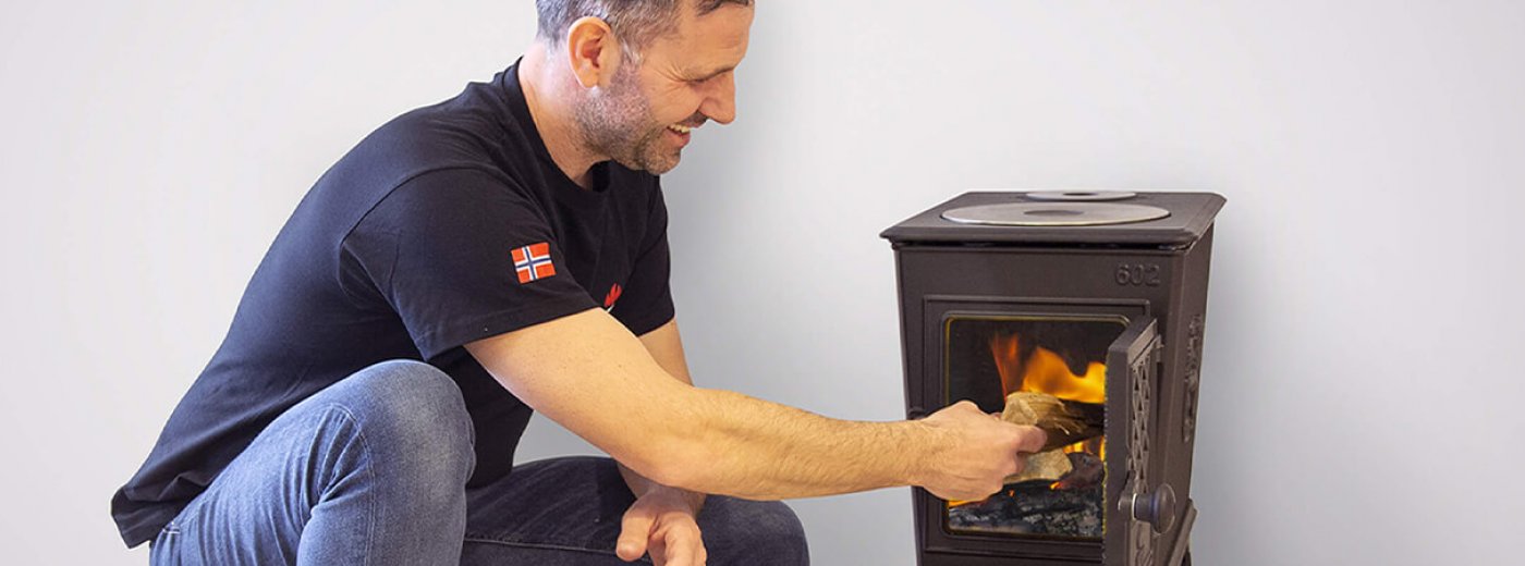 Mann sitter ved siden av vedovnen Jøtul F 602 ECO