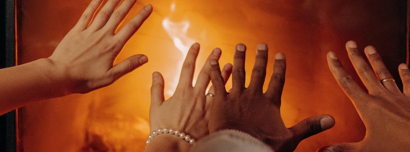 Hender som varmer seg på peisen