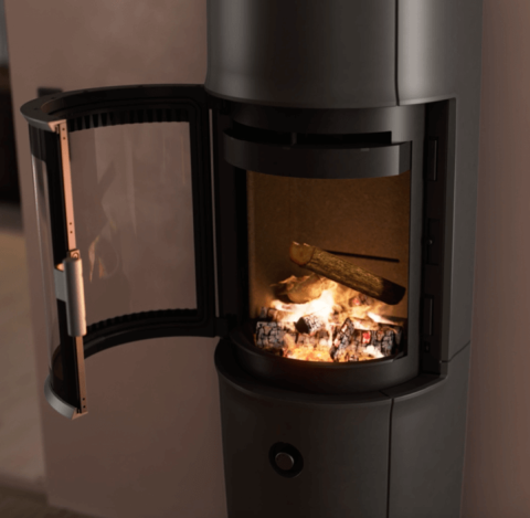 Moderne rom med stor svart Jøtul F 174 vedovn med åpen dør, pudderlilla vegger