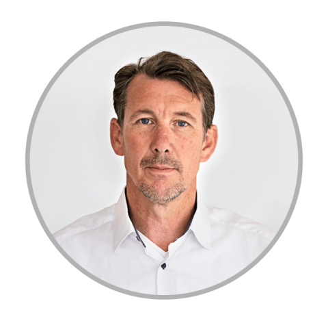 Portrett av mann med brunt hår og blå øyne, iført en hvit skjorte