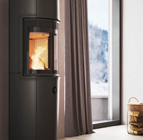 Moderne rom med stor svart Jøtul F 176 vedovn, pudderlilla vegger og snødekt fjellutsikt